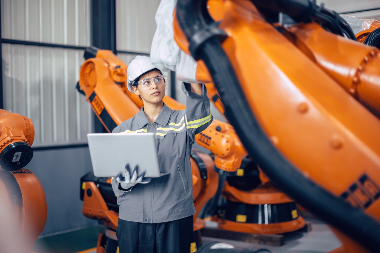 Ingenieurin prüft Roboterarm im Montagewerk – präzise Automatisierung mit TECOncept IO-Link Produkten.